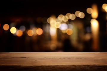 background Image of wooden table in front of abstract blurred restaurant lights