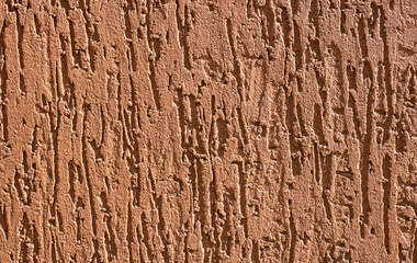 Decorative relief adhesive plaster. Brown stucco wall. The brown background of the wall.