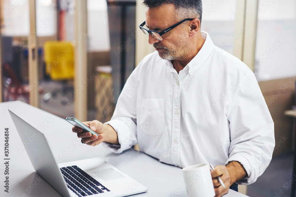 Aufkleber concentrated handsome ceo in eyewear checking email receiving notification on smartphone, matured bu