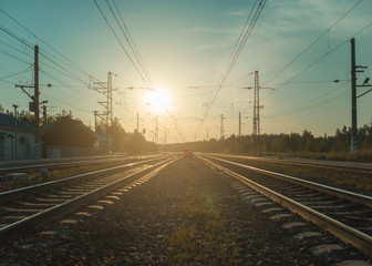 Fototapeta na wymiar Landscape with railroad tracks and red signal semaphore in the rays of sunset