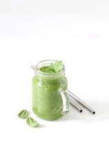 Green smoothie with parsley and spinach with a metall straw on a light background