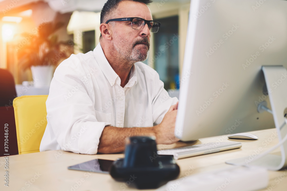 Aufkleber pensive experienced entrepreneur in optical eyeglasses browsing internet websites and reading inform