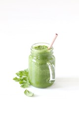 Green smoothie with parsley and spinach with a bamboo straw on a light background