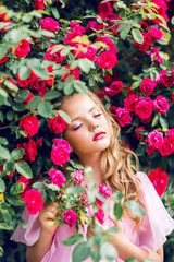 beautiful girl on a background of pink roses. Young model in a blooming garden
