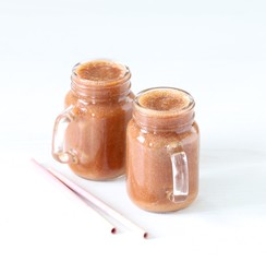 Fresh plum smoothie in a jar with a bamboo straw on a light background