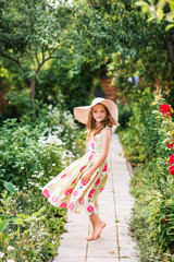 girls in a hat and dress spinning in nature in summer. Happy child in the garden