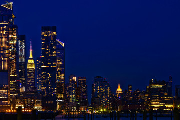 Plakat Manhattan skyline viewed from Weehawken New Jersey at dusk featuring illuminated buildings