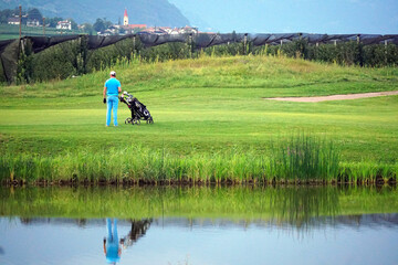 Golfer with golf cart watching a partner.