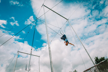 kid having swing on a high flying trapeze, boy learning acrobatic