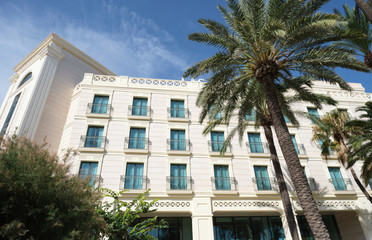 Modern hotel building with blue windows and palm trees in Valencia, Spain.