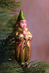 Antique Christmas tree toy in the form of a clown playing a pipe, glass Christmas decoration, macro photography, selective focus. 