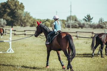 A little girl is learning to ride a horse.