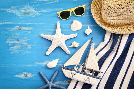 wooden vintage boat, towel, boat and sea shells over blue background