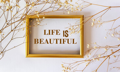 Life is beautiful, the text is written on a white background and a gold frame framed with dried flowers