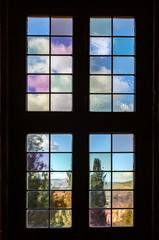 Old a window with multi-colored glass that overlooks a garden.