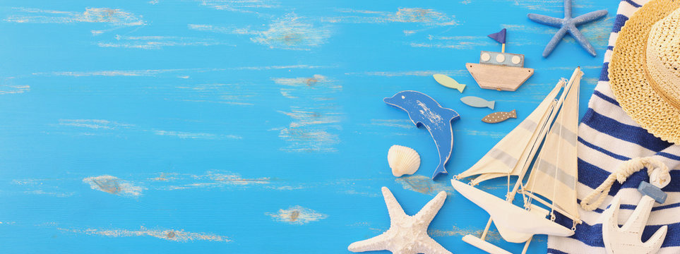 wooden vintage boat, dolphin, towel, boat and sea shells over blue background