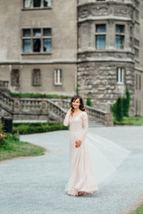 Fototapeta na wymiar A girl in a light pink dress against the background of a medieva castle