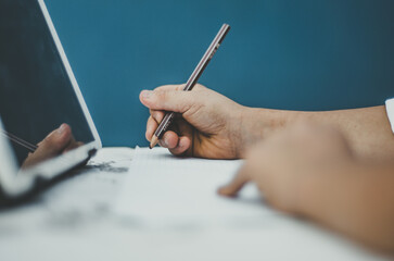 Close up of  a child's hand writing with pencil on paper, concept: online learning, home schooling, distance schooling