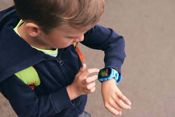 Wearable kids baby  calls mom and location tracking with touch screen and voice service, blue multicolored electronic gadget with rubber wristband for children. Close up boy with copy space. Time cloc
