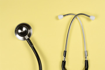 Black medical stethoscope, the phonendoscope, close up on yellow background,