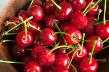 shiny red cherry berries on a plate in the hands of a child, selective focus