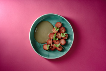 Erdbeeren Dessert mit grünem Salat und Sonnenblumenkernen auf türkisem Teller mit pinkem Untergrund