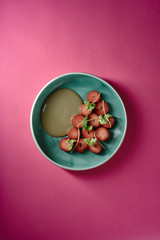 Erdbeeren Dessert mit grünem Salat und Sonnenblumenkernen auf türkisem Teller mit pinkem...