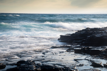 Fototapeta premium Splashing stormy windy sea waves on a rocky seashore