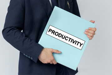A businessman holds a folder with documents, the text on the folder is - PRODUCTIVITY