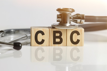 CBC the word on wooden cubes, cubes stand on a reflective white surface, on cubes - a stethoscope.