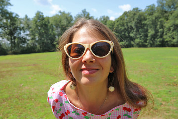 Portrait of smiling woman with long brown hair in sunglasses.