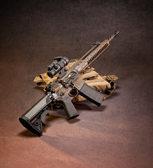 AR 15 style rifle displayed on top of gear, shot in studio.