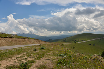 Fototapeta premium the roadbed is uneven, winding, passes through mountains and cliffs. Clouds are dark, low, with rain. A thick white fog is spreading along the road.