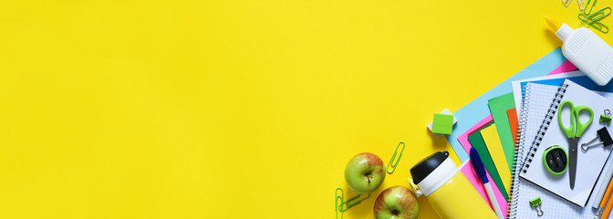 Back to school. School supplies and an apple on a yellow background. Layout of school accessories.Distance learning.