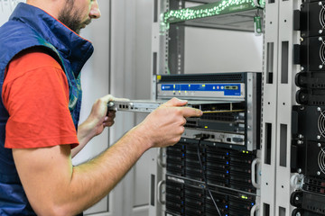 Updating the hardware part of the data center server room. The technician installs a new server board in the ISP's central router