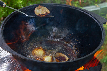 Cooking pilaf in a cauldron on the grill outside in the summer