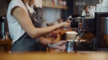 Cafe workers standing indoors and making fresh drink by using special machine. - Powered by Adobe