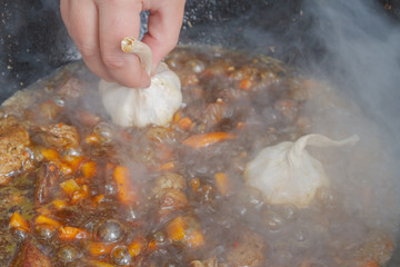 Cooking pilaf in a cauldron on the grill outside in the summer