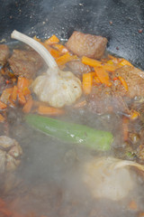 Cooking pilaf in a cauldron on the grill outside in the summer