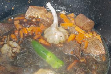 Cooking pilaf in a cauldron on the grill outside in the summer
