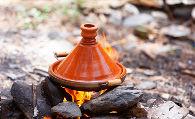 Moroccan Tajines cooked on wood fire; cooking in traditional moroccan tajine pot over open fire;...