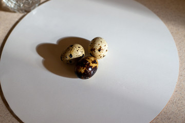 Three quail eggs are laying on the board, ready to be cooked, kitchen