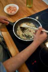 Close up of sauteed onion and garlic in the frying pan. Man preparing dinner. Cooking at home concept