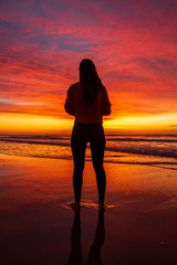 Young woman watching the sunrise on the beach