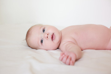 small child, baby lies on his stomach and smiles. On a white background. Newborn baby. three months old baby. A baby of European appearance. selective focus