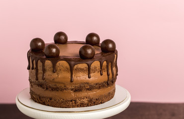 Chocolate birthday cake on pink background.