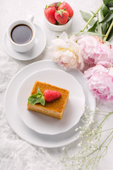 Piece honey multi layer cake, leaf mint, strawberry on plate, cup of coffee and peony. Delicate and airy composition, vertical format, top view