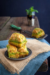 Baklava with mint tea in the back on wooden table