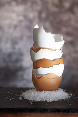 Cracked eggshell stacked on top of each other, grey background