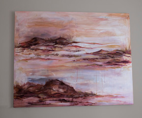 Art. View of romantic painting depicting the ocean, waves and rocks in the beach at sunset, hanging in the wall. Beautiful brushstrokes and dusk palette of pink, magenta, orange and red colors. 
